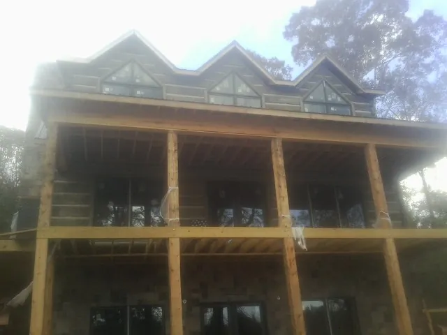 Dormers and porch framing on a large log home under construction — Roof Coating work by our crew in Minneota