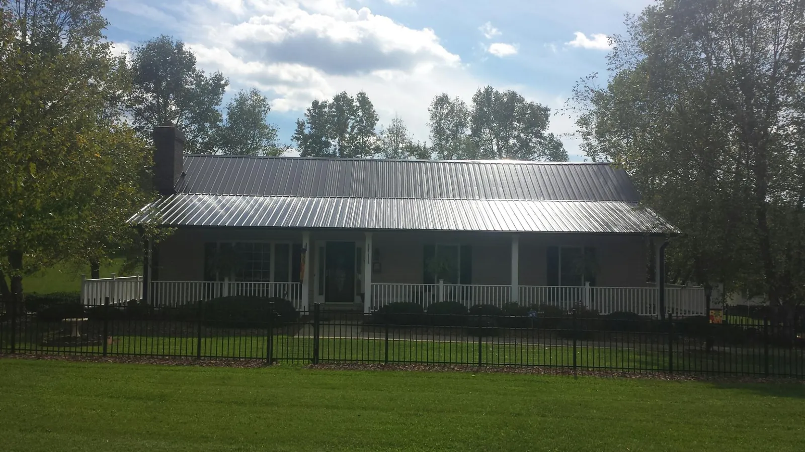 Gray metal roof on a brick ranch with a full width front porch — Gutter Guard Installation work by our crew in Minneota
