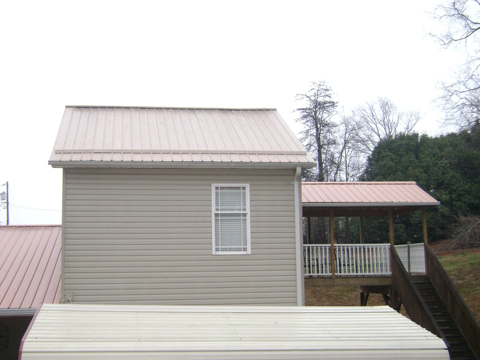 Tan metal roofs on a two story addition and attached porch, from a Roof Replacement job in Minneota