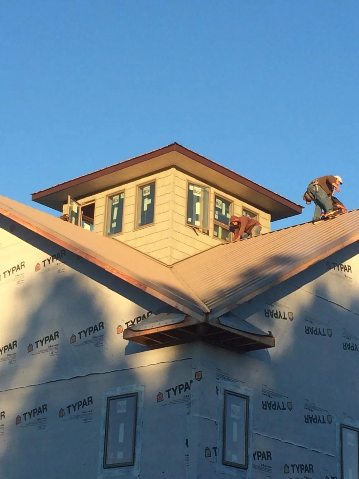 Roofers working around a rooftop cupola on a new metal roof at sunset — Roof Waterproofing in Minneota by Roofing Brothers